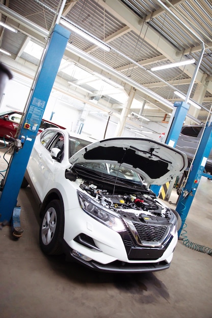 Modern beautiful car with open hood at a service station in the process of being repaired