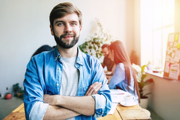 Modern beautiful confident young business man in smart casual wear stands in front of successful business team that working with graphs and documents