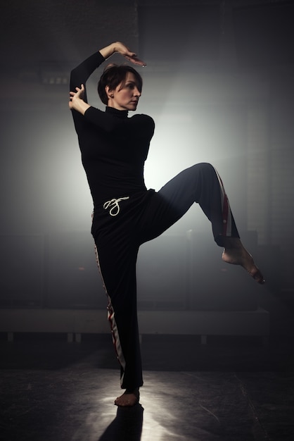 Современная красивая танцовщица в черной одежде позирует