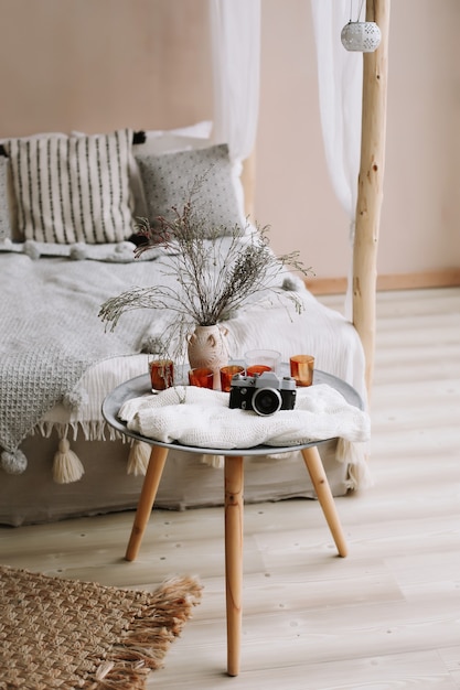 Interno moderno della camera da letto con letto con baldacchino in legno e cuscini, coperta e comodino