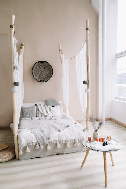 современный интерьер спальни с кроватью с деревянным балдахином и подушками, одеялом и прикроватной тумбочкой