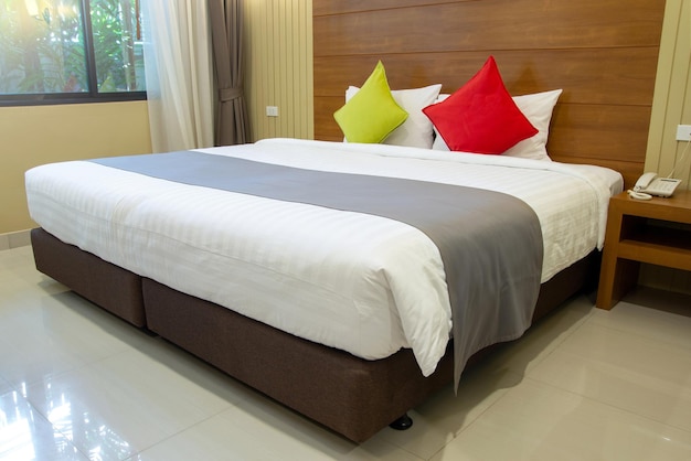 Foto interiore moderno della camera da letto con il cuscino variopinto sul letto