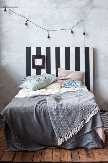 Modern bedroom with simple furniture, gray bedding and wooden headboard.