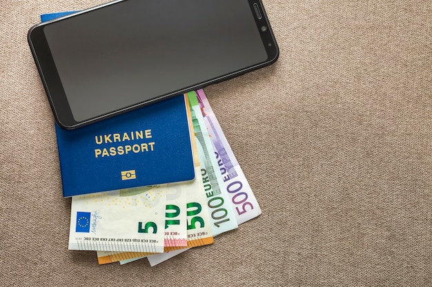 Modern black cellphone Euro money banknotes bills and travel passport on copy space background Travelling light comfortable journey concept