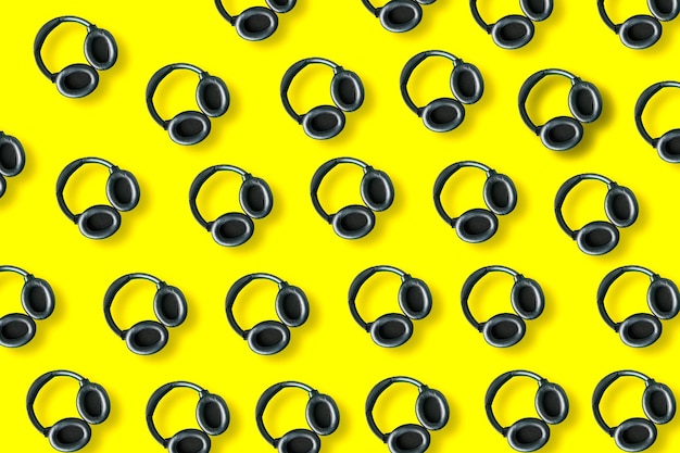 modern black headphones pattern isolated on bright yellow background Copy space