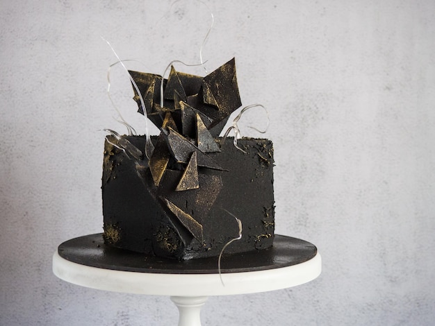 Photo modern black square chocolate cake covered with velour and decorated with isomalt and chocolate bar