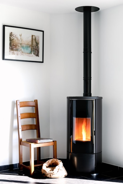 Modern black stove with burning flames and pellet bag in a living room