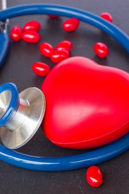 Modern blue stethoscope with red heart close up