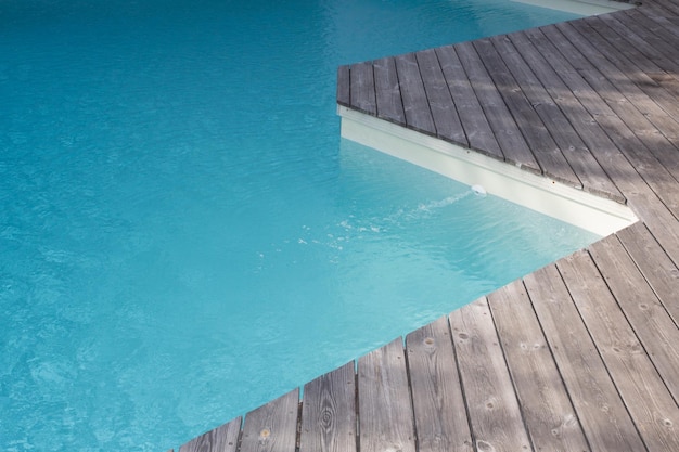 Современный голубой бассейн с деревянным настилом из тикового дерева
