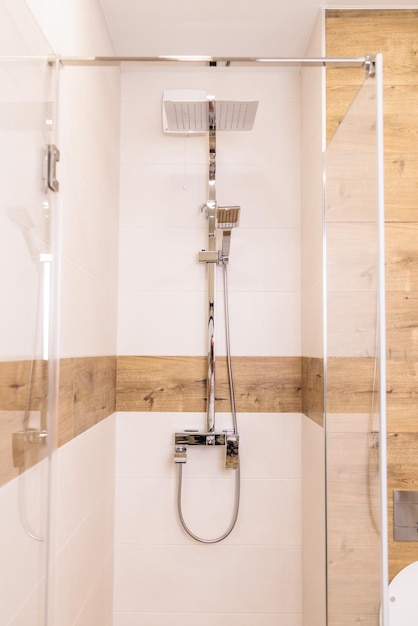 Modern bright shower cabin closeup with water equipment vertical wooden background