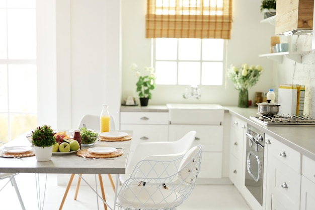 Modern bright white kitchen interior with wooden and white details healthy breakfast with fruits and