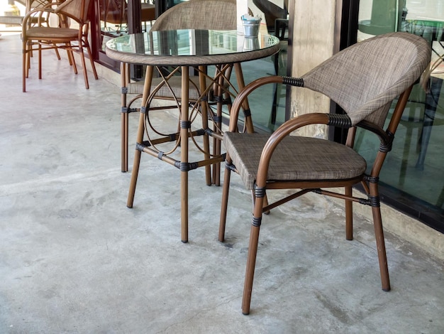 카페 외부 유리벽 근처에 있는 현대적인 갈색 의자와 둥근 유리 테이블