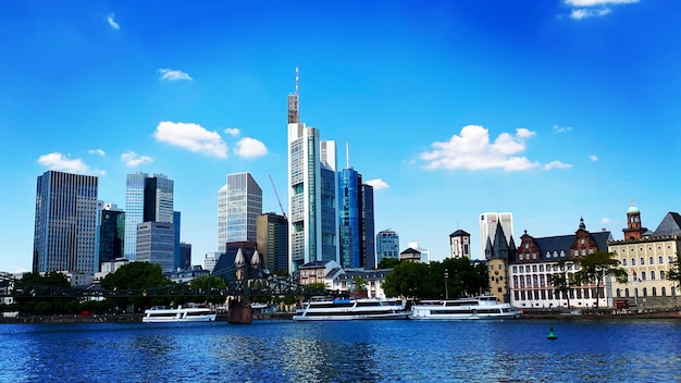 Modern buildings by river against blue sky