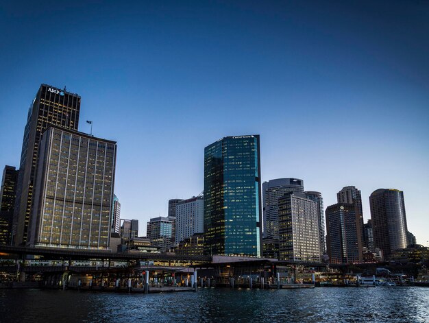 Modern buildings by river against clear sky