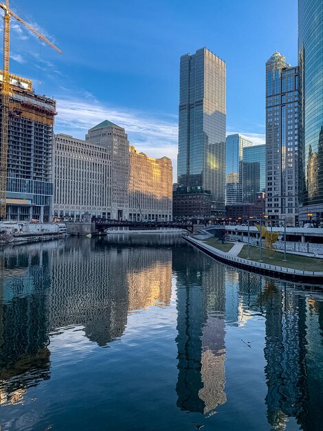 Modern buildings by river against sky in city