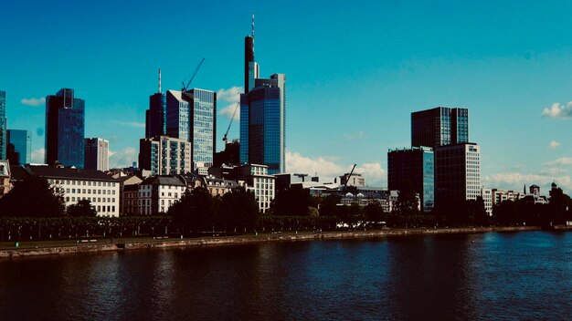 Modern buildings by river against sky in city