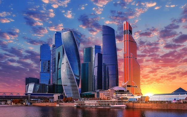 modern buildings by river against sky during sunset