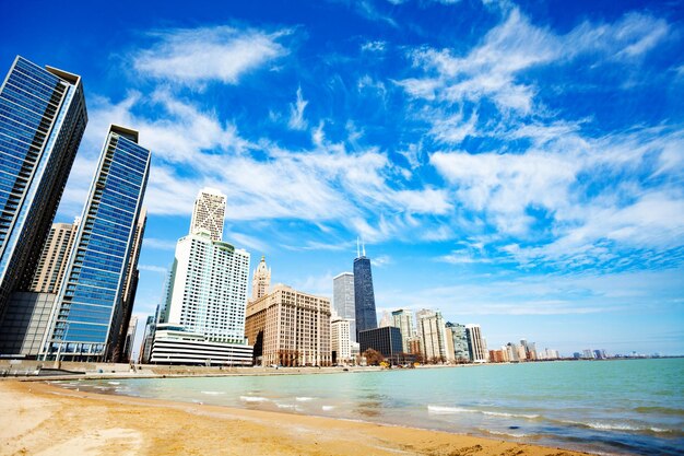 Modern buildings by sea against blue sky