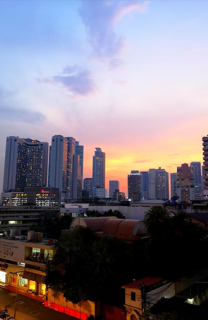 Modern buildings in city against sky during sunset