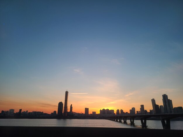 Modern buildings in city against sky during sunset