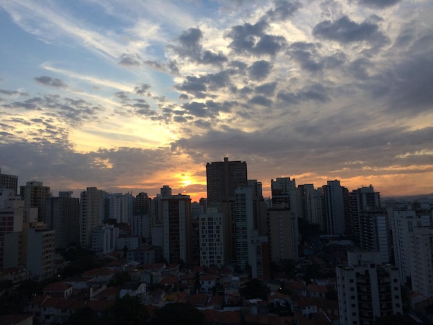 Modern buildings in city against sky during sunset