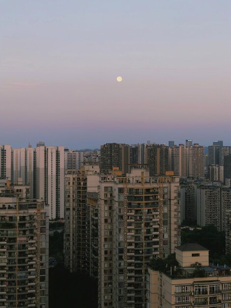 Modern buildings in city against sky during sunset