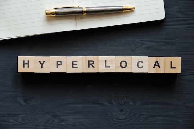 Modern business buzzword - hyperlocal. Top view on wooden table with blocks. Top view.