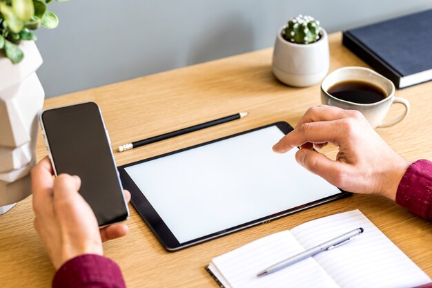 Composizione aziendale moderna in ufficio a casa con freelance, schermo tablet mock up, pianta, note, telefono cellulare e forniture per ufficio in un elegante concetto di arredamento per la casa.