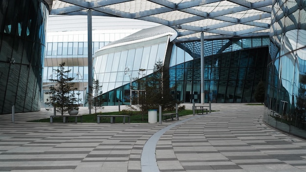 Modern business district courtyard and building exterior with blue windows benches and trees