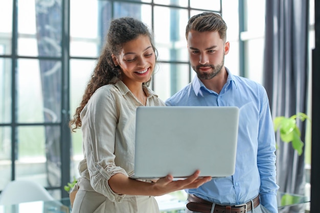 Modern business people are working using laptop and smiling while standing in the office