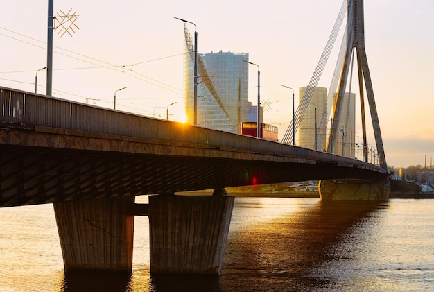 Photo modern business skyscrapers and vansu bridge above daugava river in riga in latvia. at the sunset in the evening