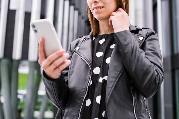 비즈니스 센터 근처에서 스마트폰을 사용하여 온라인으로 이야기하는 현대 비즈니스 여성
