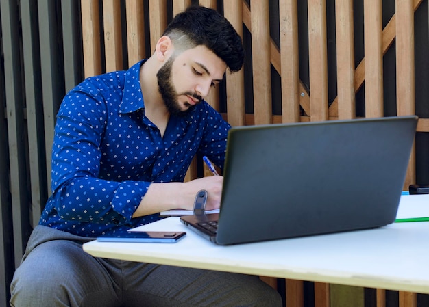 Modern businessman making notes in day planner while having rest in cozy cafe