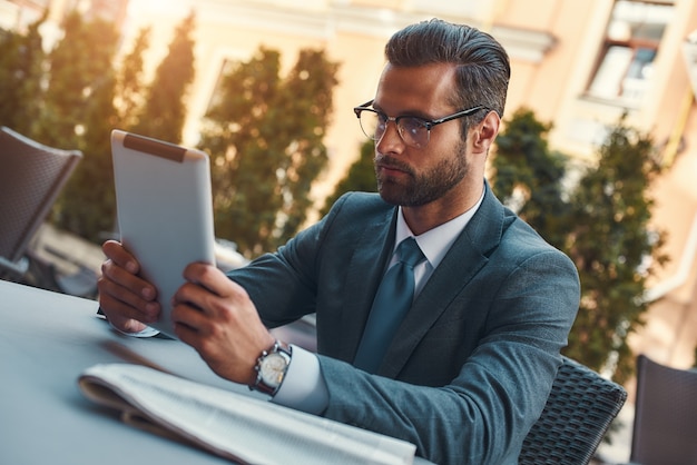 Modern businessman portrait of handsome bearded businessman in eyeglasses working with touchpad