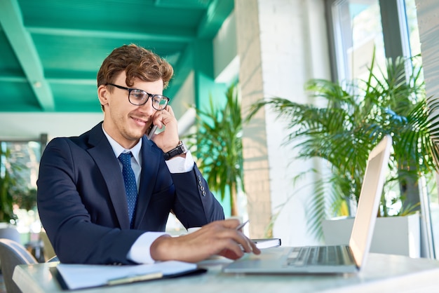 Uomo d'affari moderno che parla dal telefono mentre lavorando