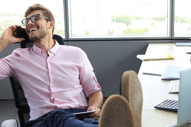 Photo modern businessman talking on the phone while sitting in the office.