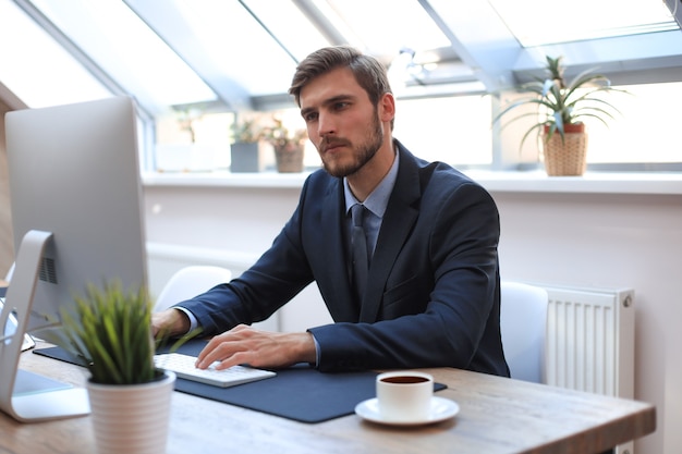 Foto uomo d'affari moderno che pensa a qualcosa mentre è seduto in ufficio.