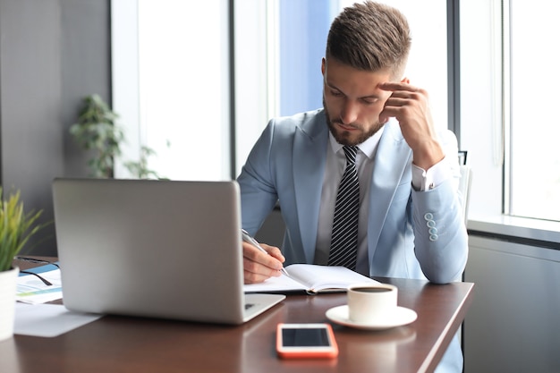 Uomo d'affari moderno che pensa a qualcosa mentre è seduto in ufficio.