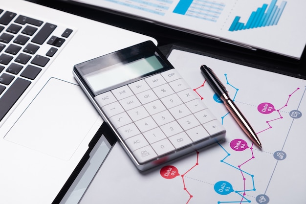 Modern calculator is on laptop and on sheet with a graph