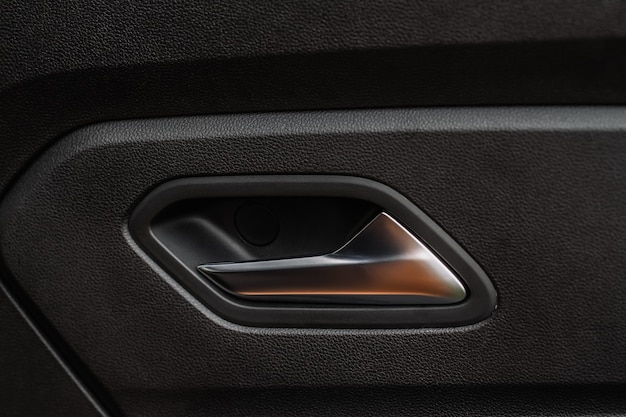 Modern car interior door handle close up. Metallic Car door opener handle inside.