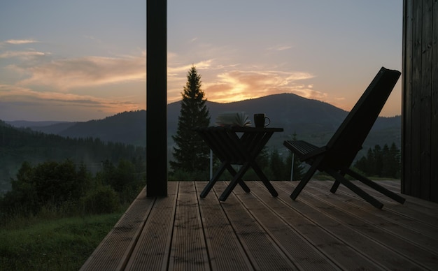 Sedia e tavolo moderni sulla terrazza con vista sulle montagne al tramonto