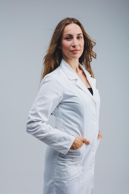 Современный веселый врач в белом халате на сером фоне женщина-врач с улыбкой на лице
