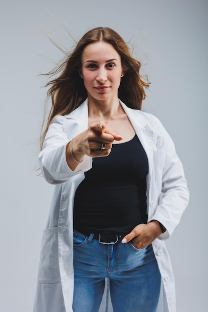 Medico allegro moderno in un camice bianco su sfondo grigio donna medico con un sorriso sul suo viso