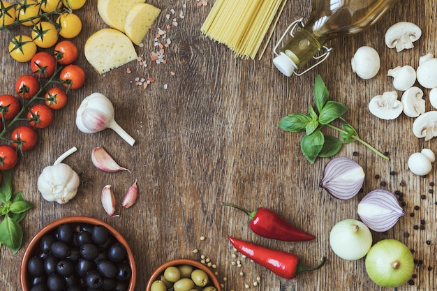 Modern composition of fresh food and ingredients on the vintage wooden table in the kitchen. Italian taste and look