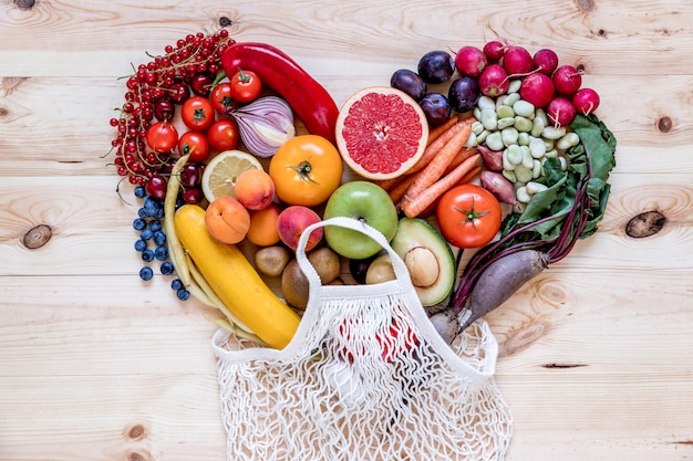 Modern composition of fresh healthy vegetables and fruits in heart shape on the wooden kitchen table