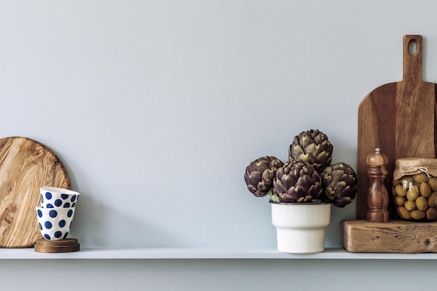 Modern composition on the kitchen interior with vegetables cutting board food herbs kitchen accessories and copy space on the shelf