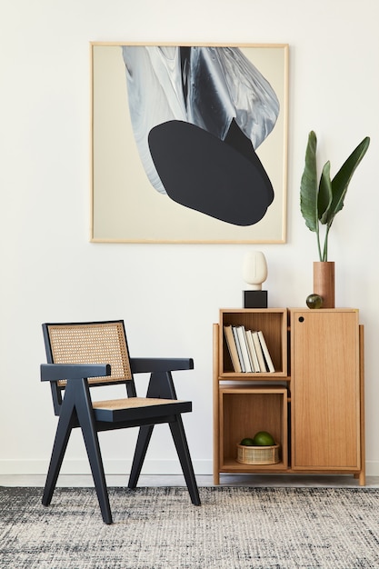 Modern composition of living room interior with design black chair, wooden bookcase, tropical leaf in vase, book, carpet, decoration and abstract painitngs on the wall..