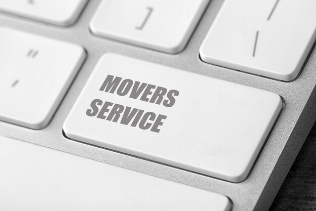 Фото Современная компьютерная клавиатура с фразой movers service на крупном плане стола