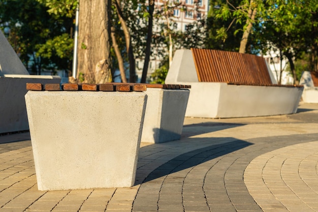 Modern concrete bench and concrete poufs covered with wooden
slats in the city park.