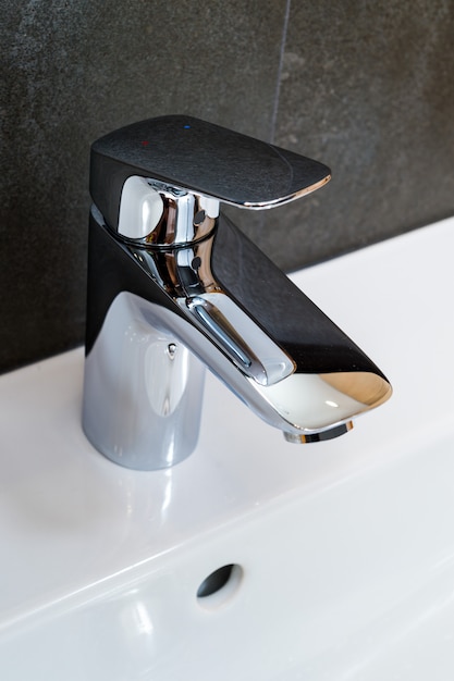 Photo modern and contemporary bathroom detail in a luxury home, tap chrome faucet washstand